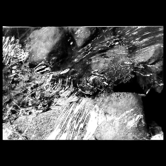 Espiral captada de agua en movimiento sobre rocas de un río, editada en blanco y negro